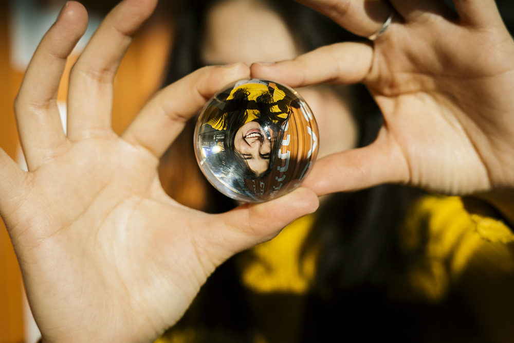 Gabriela Herman photo of a woman holding a lens ball with her portrait showing