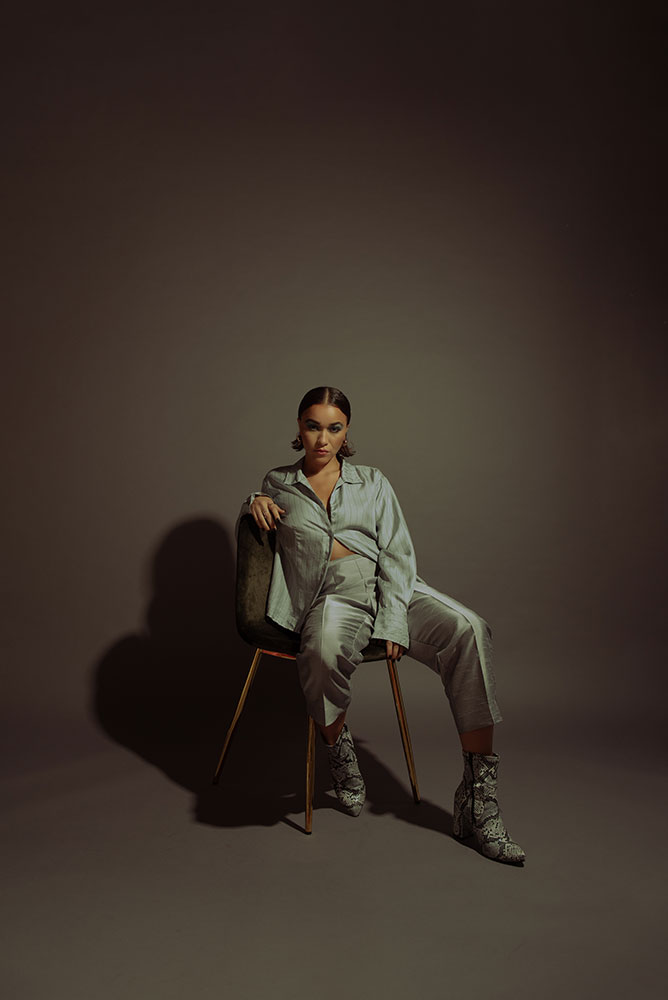 Inari Briana portrait of a model sitting in a chair with a brown background